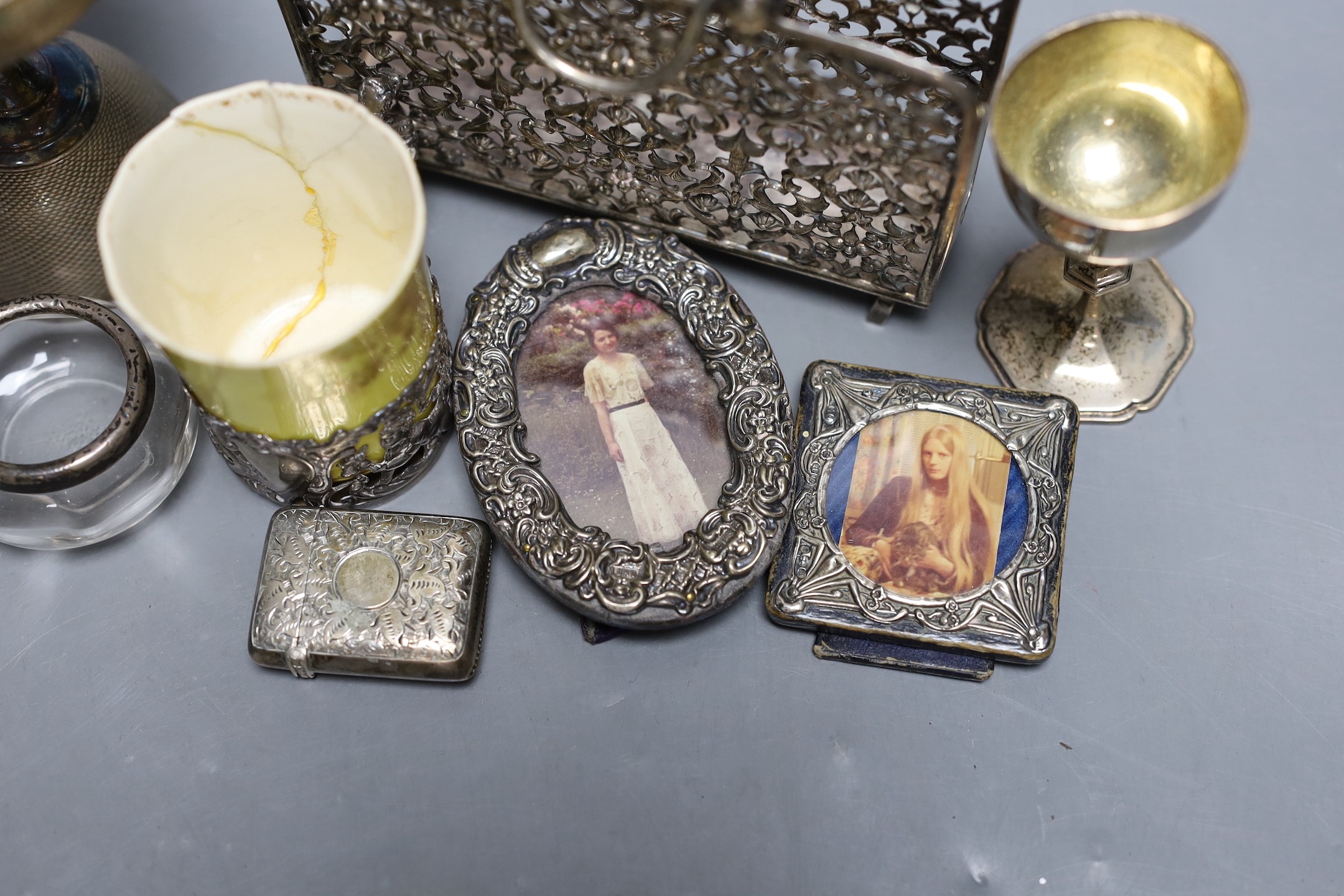 A small group of collectable items including a silver stationary rack, Laurence Emanuel, Birmingham, 1901, height 9.7cm, a silver communion goblet, silver mounted porcelain coffee cup, silver mounted glass vase, silver v